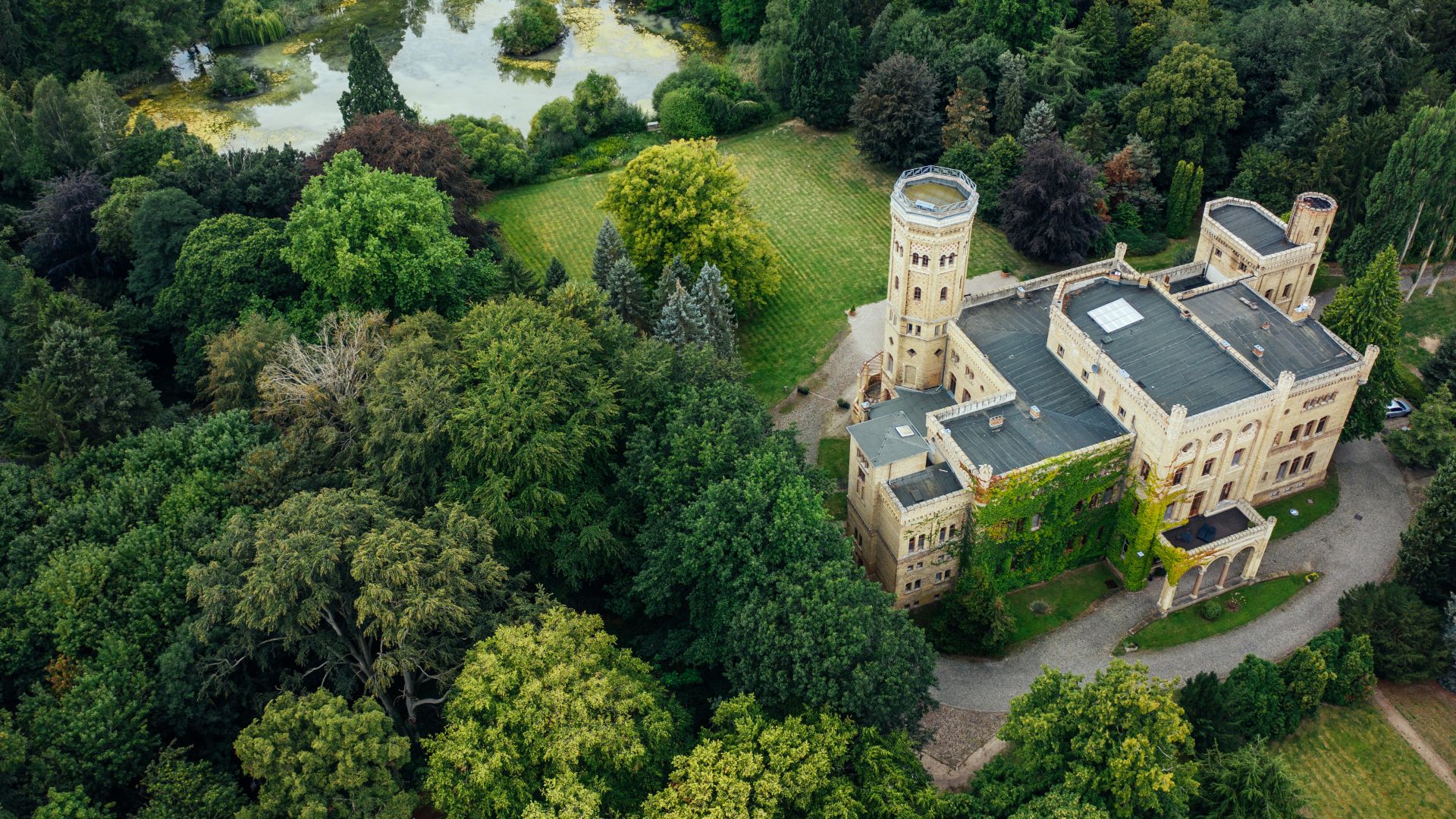 Aerial view of Schloss Neetzow, surrounded by dense forest and a small pond.