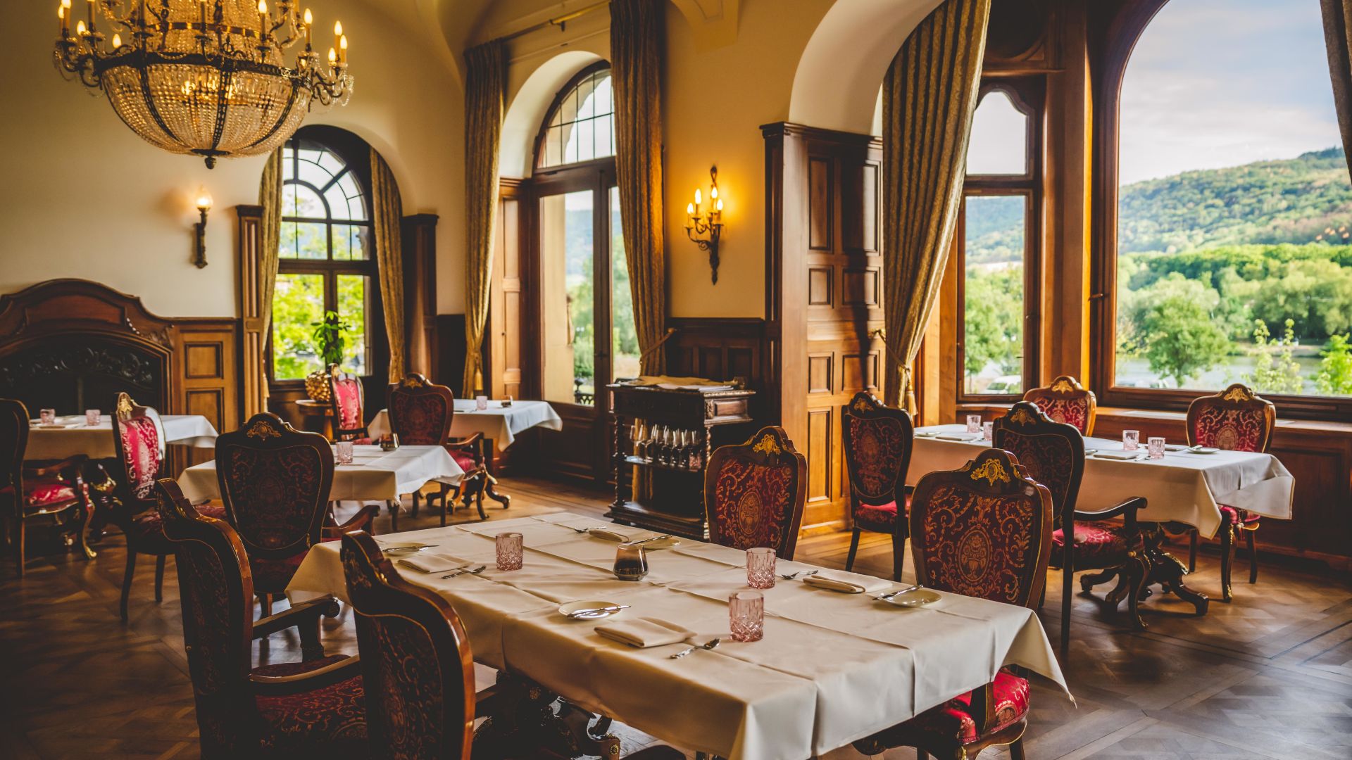 Luxurious restaurant with chandelier and views of the Mosel landscape in Schloss Lieser
